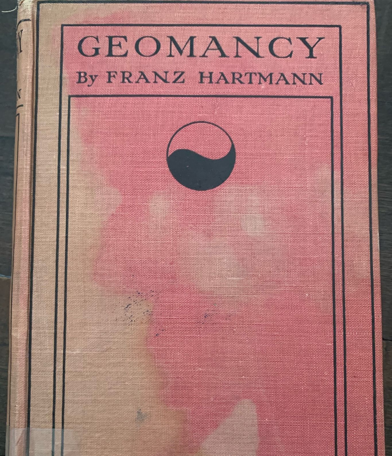 Reddish worn cover titled “GEOMANCY” by Franz Hartmann with a circular symbol and library sticker.