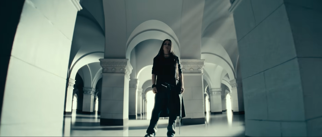Amy Lee standing between large white archways in the Evanescence music video for Who Will You Follow.
