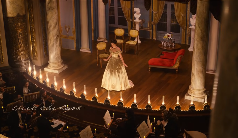Sue Gilbert performing on a warm-lit opera stage in a gold gown during the Dickinson season two Split the Lark episode.