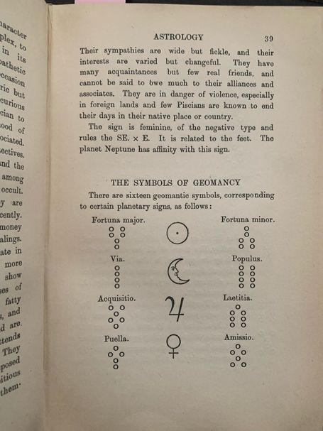 Open book showing astrology text and geomantic symbols with planetary signs.